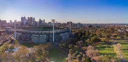 Aerial shot of the Melbourne Cricket Ground with Melbourne city skyline behind